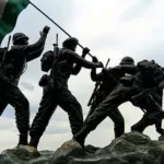 indian flag being carried by statues of indian soldiers